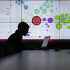Student in silhouette in front of large screen display with infographic