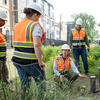Four people in hardhats and vests investigating a bioinfiltration basin